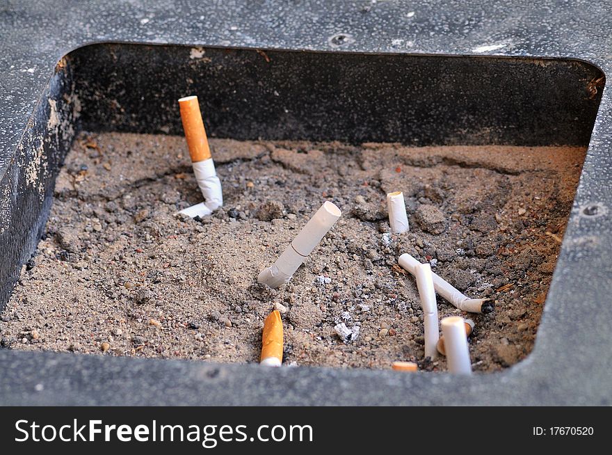 Smoked end cigarettes in a ashtray filled with sand. Smoked end cigarettes in a ashtray filled with sand