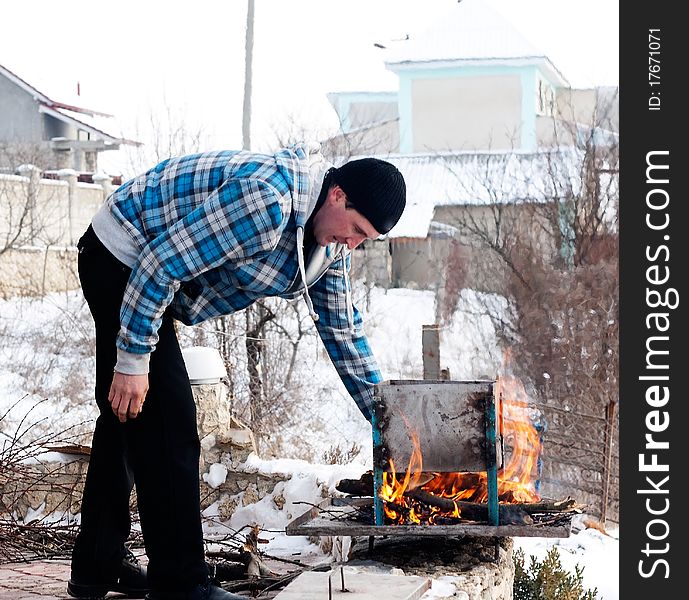 The man ignites a fire for cooking kebabs. The man ignites a fire for cooking kebabs