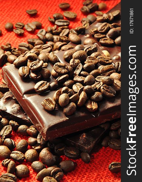 Chocolate with nuts and coffee beans on red background
