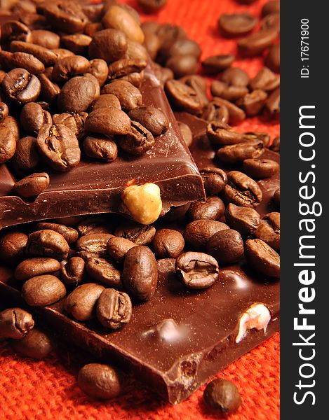 Chocolate with nuts and coffee beans on red background