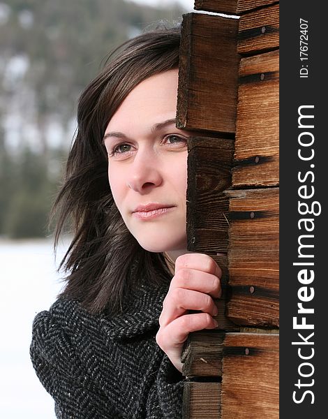 Beautiful brunette female leaning against wooden barn