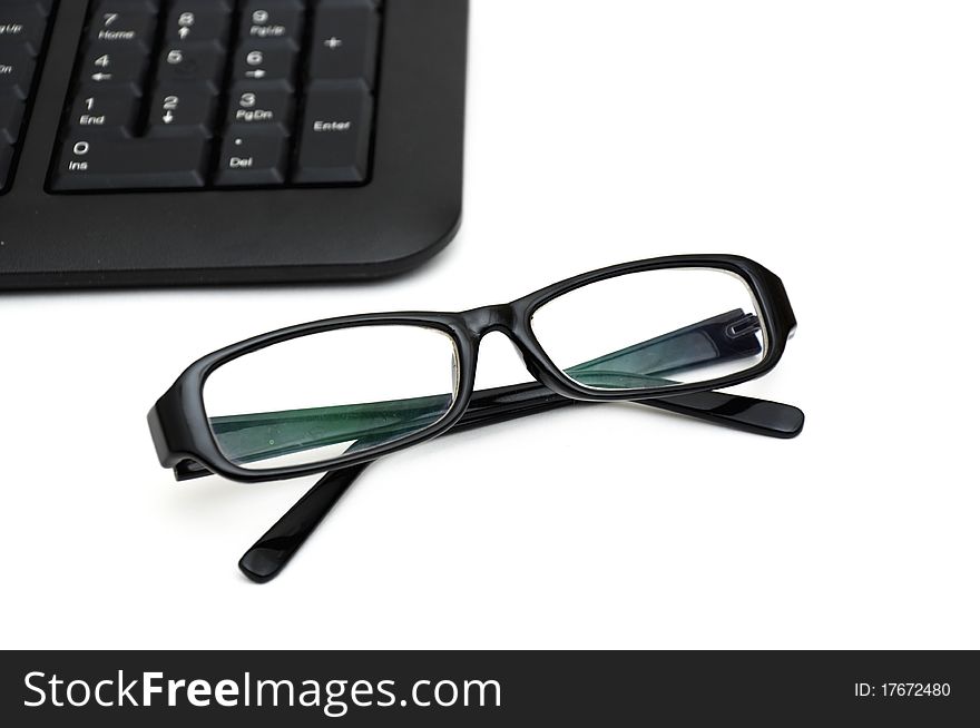 Glasses on computer keyboard isolated on white background