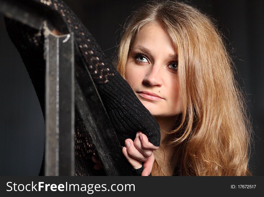 Young blond woman in black leans on  handrail. Young blond woman in black leans on  handrail