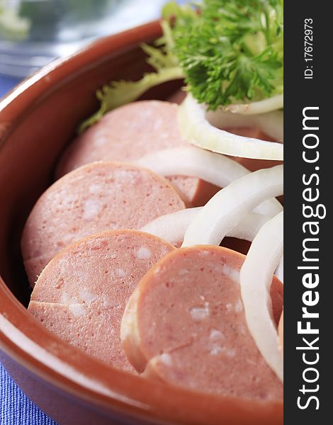 Dish of sliced sausages and onion - detail