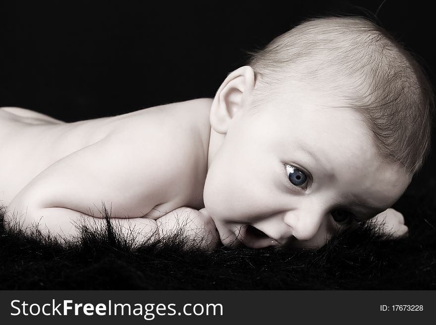 Beautiful three month old baby boy lying on black fur