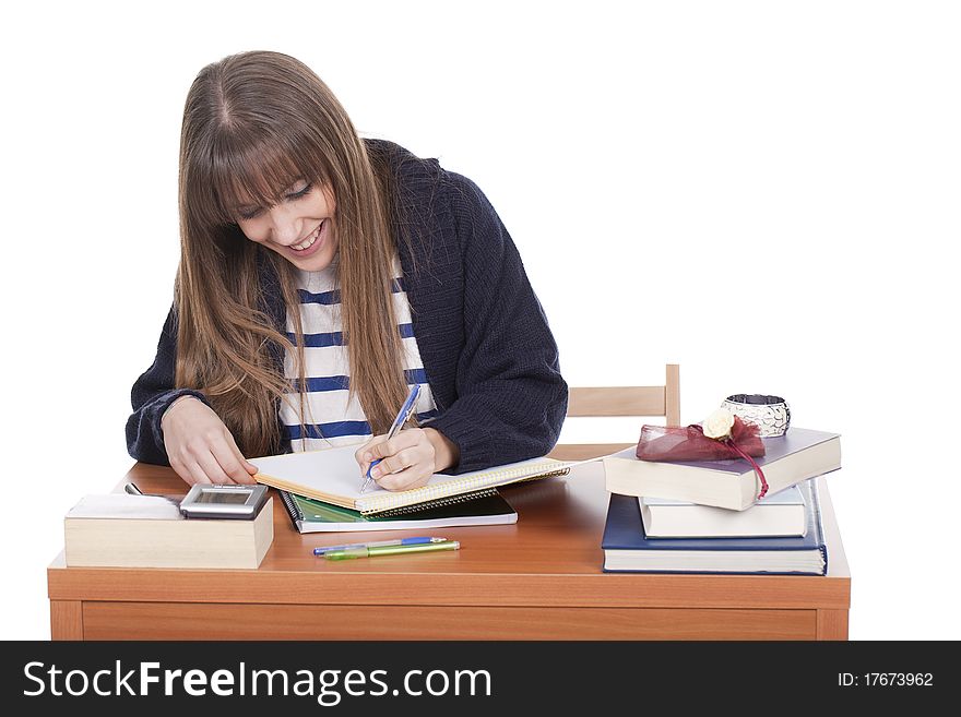 A young and student girl sitting at her desk and writing. A young and student girl sitting at her desk and writing