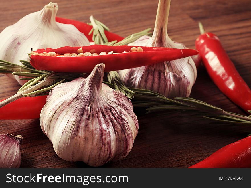 Fresh garlic with red pepper and rosemary on a table. Fresh garlic with red pepper and rosemary on a table.