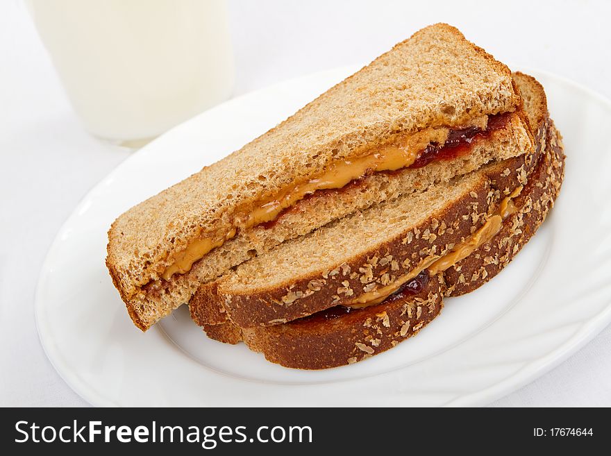 A peanut butter and jelly sandwich on whole wheat bread with a glass of milk