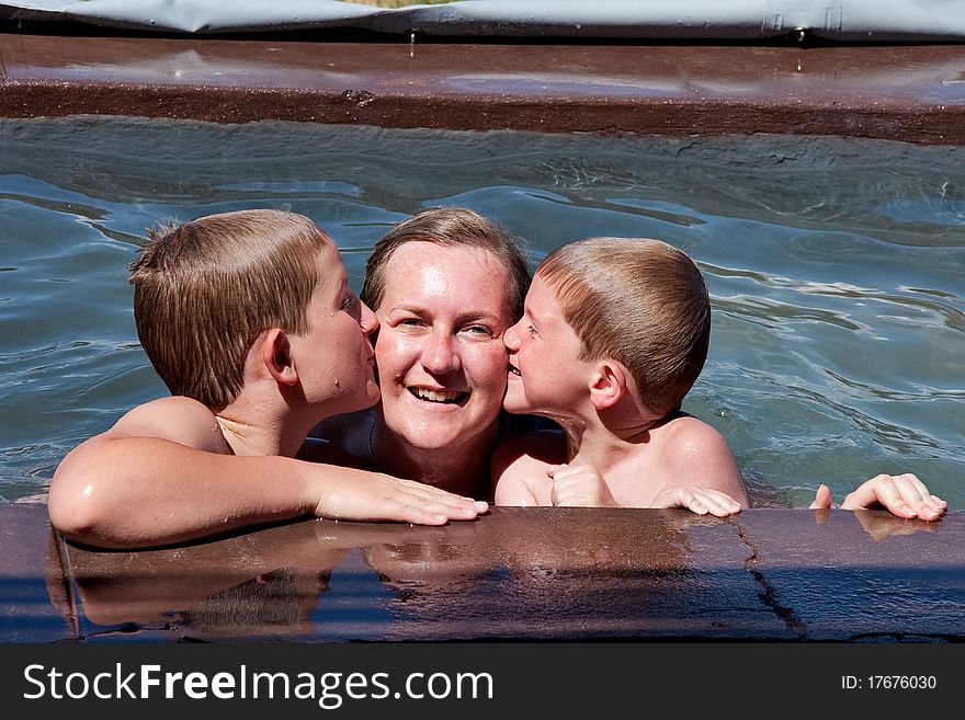 Adorable siblings kissing their mother in swimming pool. Adorable siblings kissing their mother in swimming pool