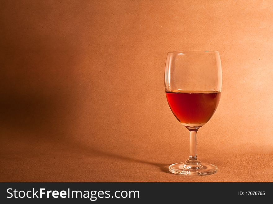 Elegant red wine glass on brown wooden background