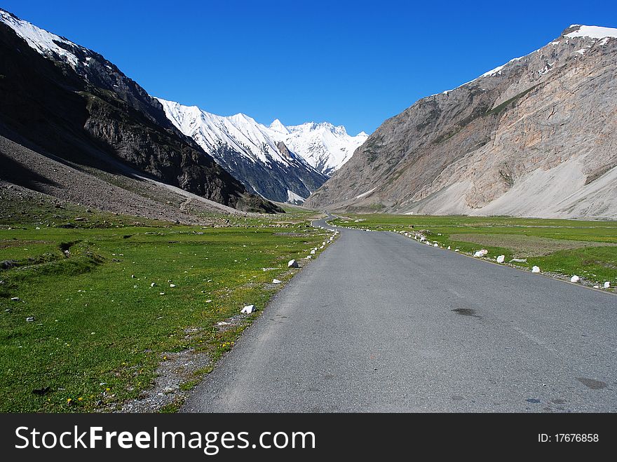 A road leading to a distant snow peak in a Himalayan valley. A road leading to a distant snow peak in a Himalayan valley.