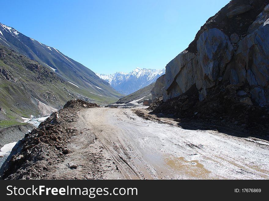 A muddy road leading to a distant snow peak in Himalayan valley. A muddy road leading to a distant snow peak in Himalayan valley.