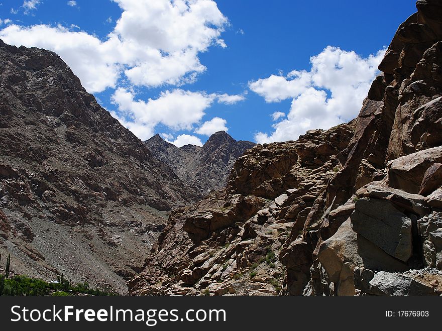 A beautiful landscape scene with white clouds hovering over a rocky mountain. A beautiful landscape scene with white clouds hovering over a rocky mountain.