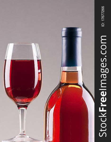 Glass and bottle of rose wine with gray background