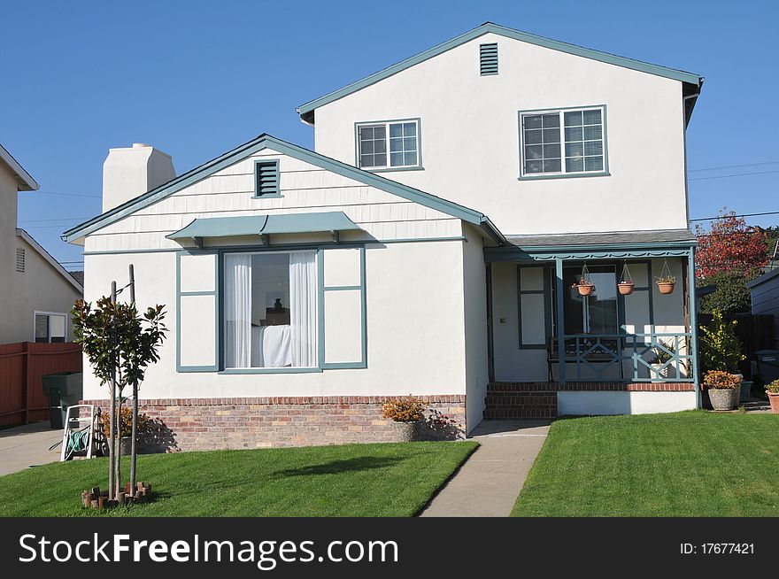 House surrounded by trees and grass with blue sky.