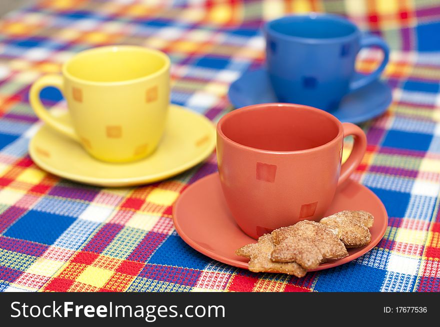 Three bright cups with cookies on a saucer. Three bright cups with cookies on a saucer