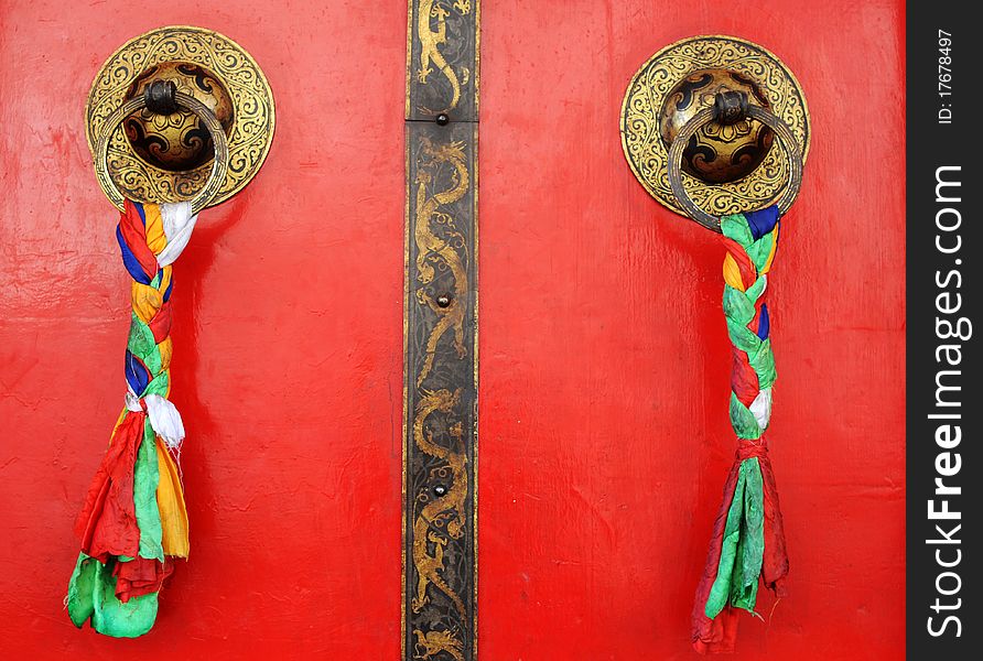 Typical Tibetan red doors with doorring and prayer flags. Typical Tibetan red doors with doorring and prayer flags