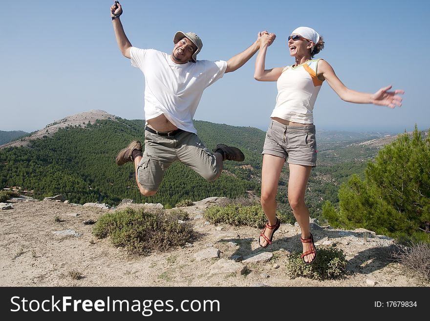 Funny young couple jumping in mountains