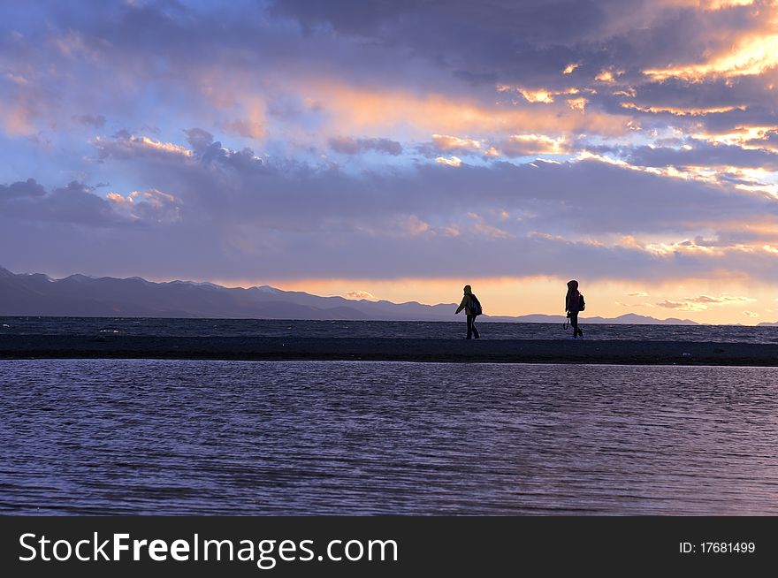 Landscape of the silhouette of two travelers at the lakeside in Tibet at sunset. Landscape of the silhouette of two travelers at the lakeside in Tibet at sunset