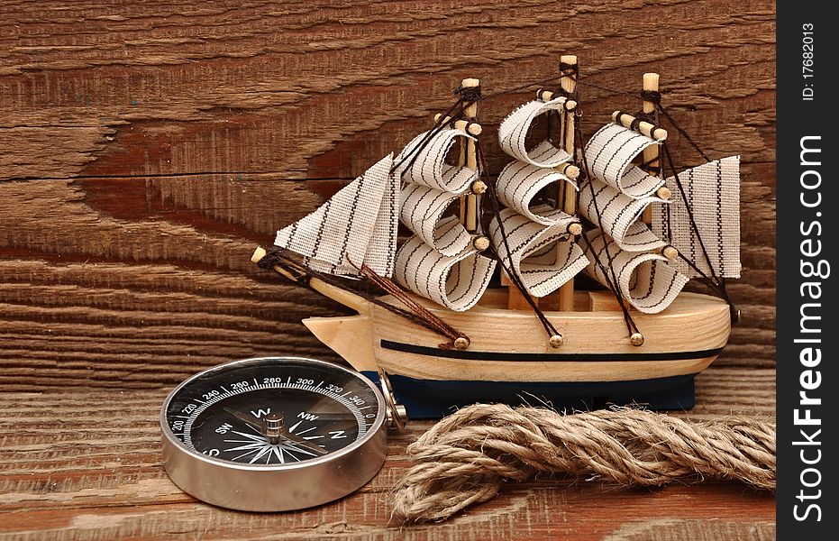 Compass, rope and model classic boat on wood background