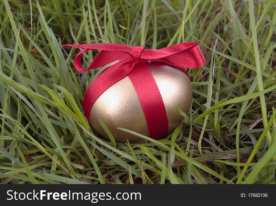 Gold easter egg and ribbon on grass. Gold easter egg and ribbon on grass
