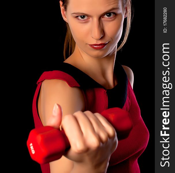 Serious woman athlete showing red dumbbell on black background. Serious woman athlete showing red dumbbell on black background