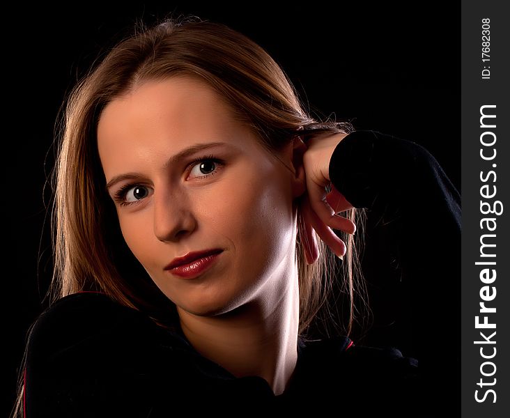 Joyful young girl looking on camera on black background