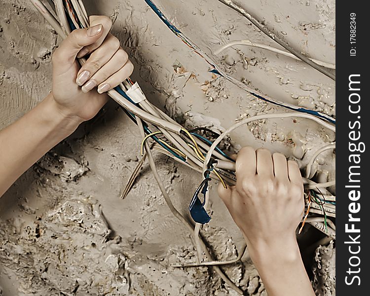 Woman hands grabbing wires to tear it on concrete wall background