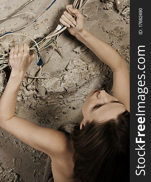 Woman pulling up grabbing the wires climbing up on the concrete wall