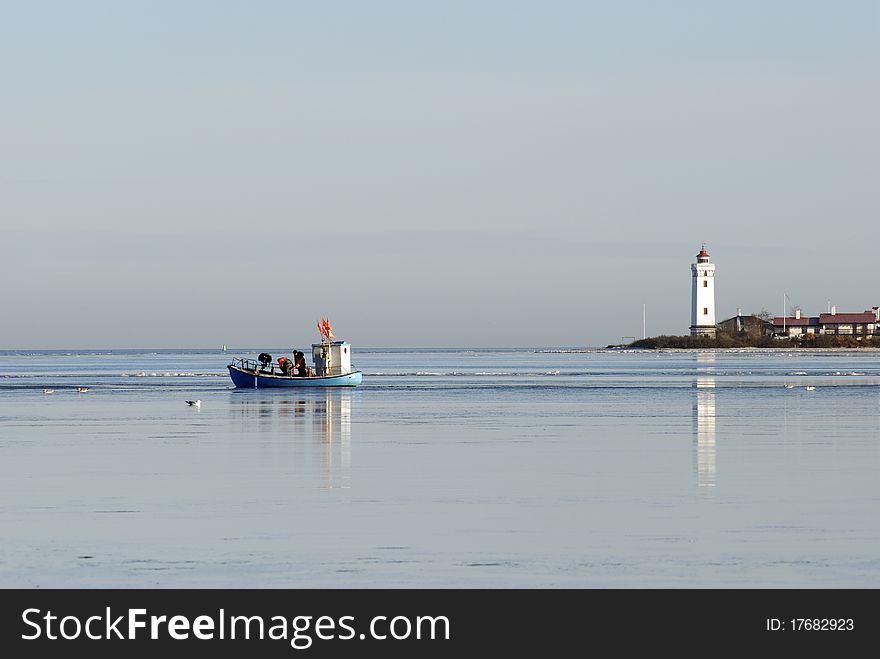 Fishing from fishing boat at open winter sea close to lighthouse in Denmark.