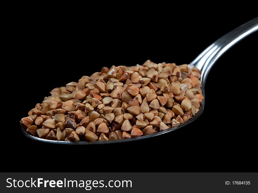 Buckwheat on spoon with black isolated background