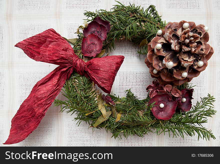 Handmade Christmas wreath made from desiccated nature products and red ribbon.