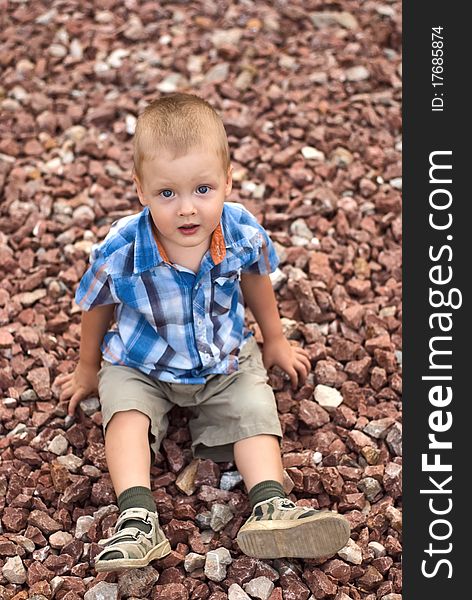 A little boy sitting on stones. A little boy sitting on stones