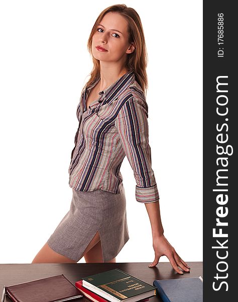 Beautiful woman teacher standing at the desk with books on top of it