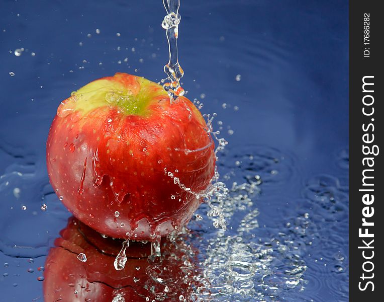 Apple and splash water over blue background