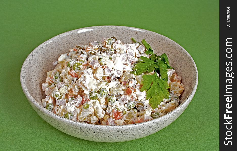 Traditional russian salad olivier in bowl on green background