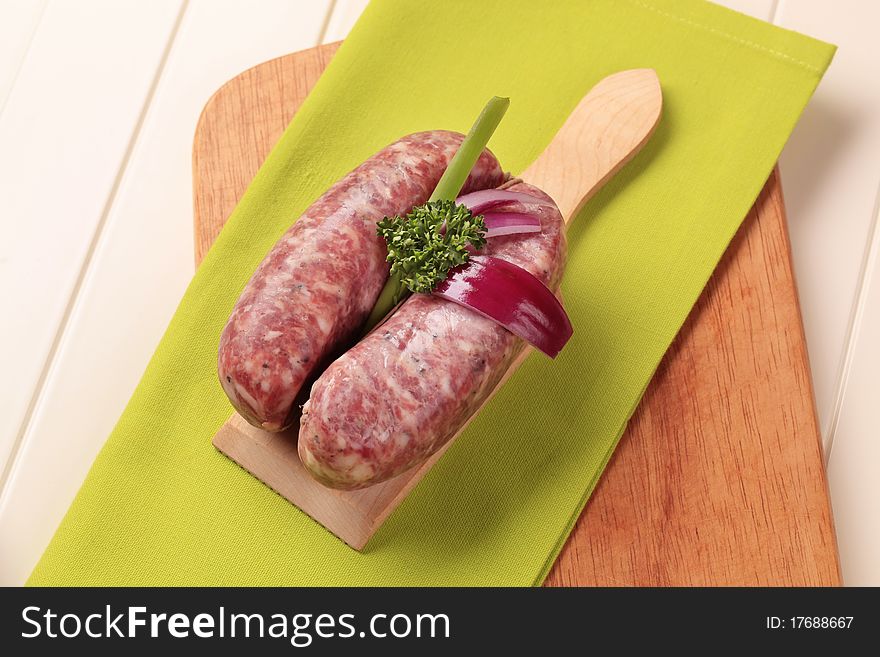 Italian sausages and Spanish onion on cutting board