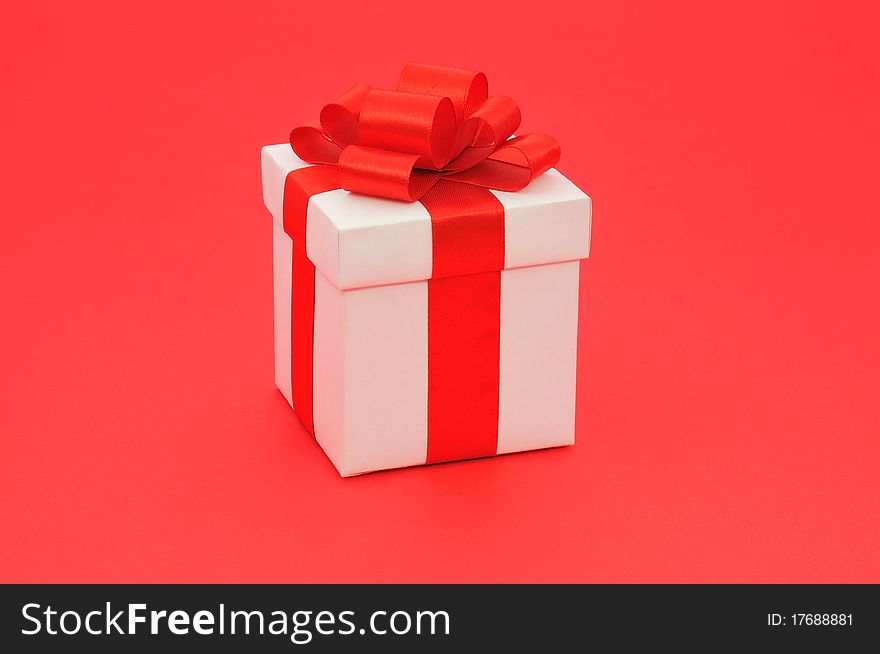 White gift box with a red bow on red background