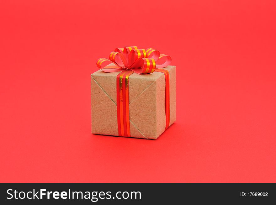 Gift box with gold and red ribbon in red background.