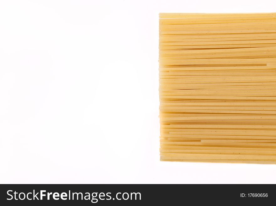Spaghetti lie on a white background on the right side of the frame, the frame is horizontal. Spaghetti lie on a white background on the right side of the frame, the frame is horizontal