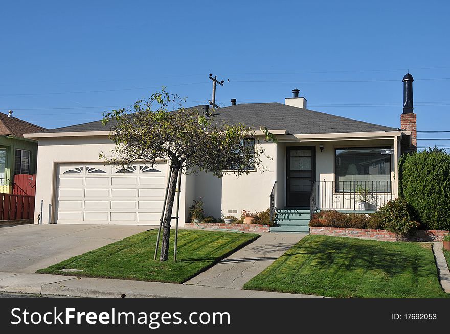 House surrounded by trees and grass with blue sky.