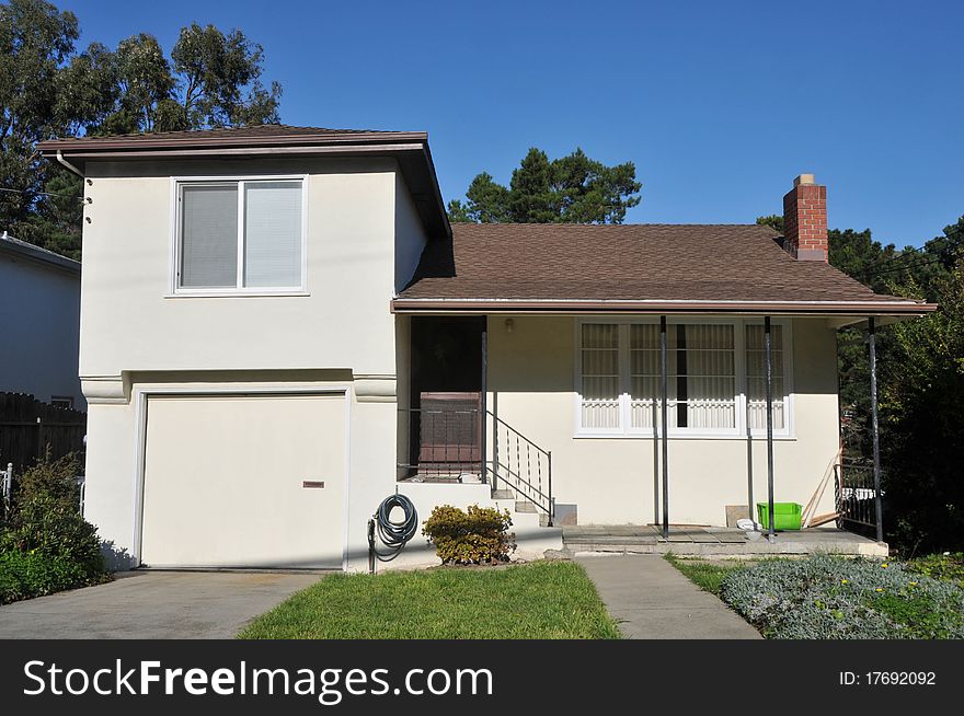 House surrounded by trees and grass with blue sky.