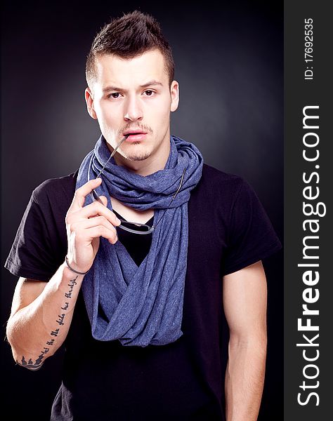 Studio shot of a handsome young male model wearing T-shirt and holding sunglasses in his mouth