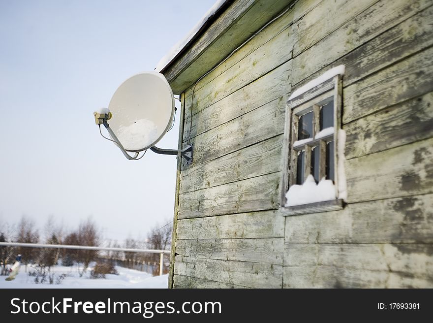 Satellite plate on a house wall winter cold and snow round