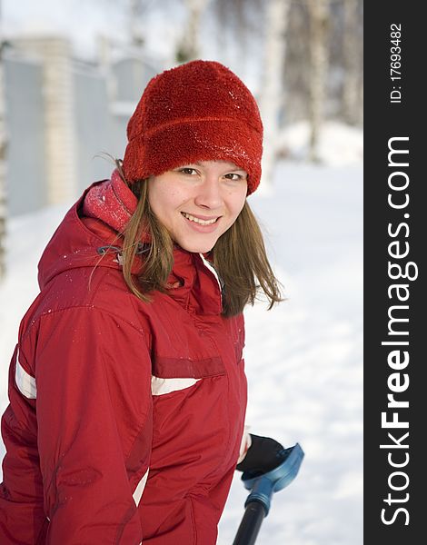 The girl in a winter red cap smiles and snow