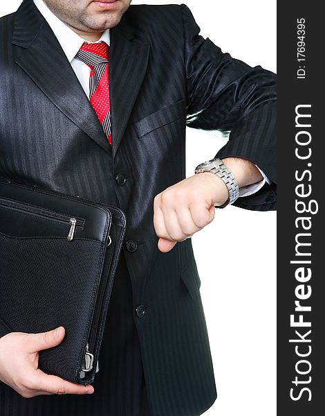 The businessman in a black suit with a portfolio looks at a watch. The businessman in a black suit with a portfolio looks at a watch