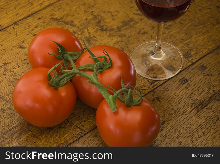 Tomatoes and a glass of red wine on an old wooden table