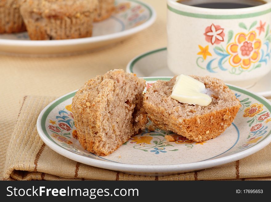 Muffin sliced open with melting butter on a plate. Muffin sliced open with melting butter on a plate