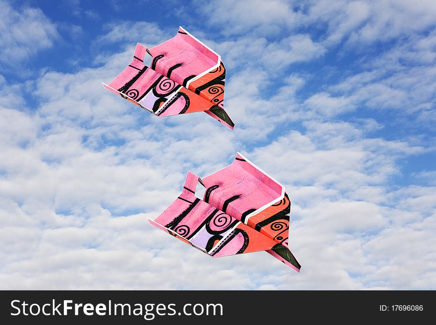 Two colored paper plane against winter clouds. Two colored paper plane against winter clouds