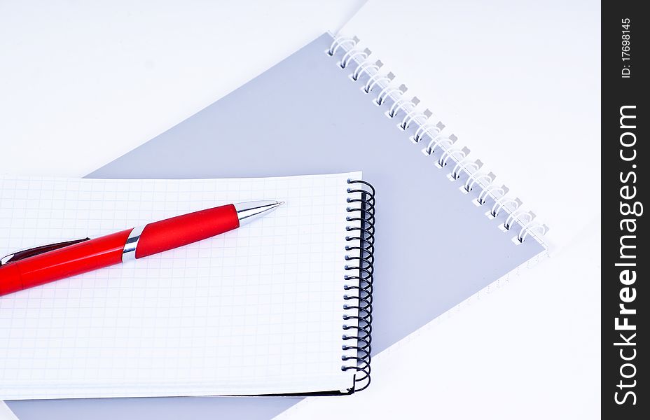 A red pen on a notebook, isolated in white background.